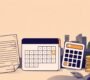 A payslip, holiday calendar, calculator, and gold coins on a desk with a UAE-inspired skyline.